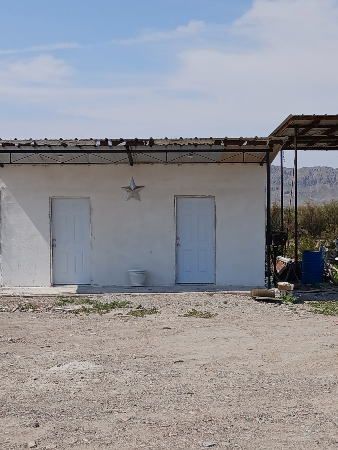 Adobe-toned bathhouse and laundry building with a shaded picnic ramada
