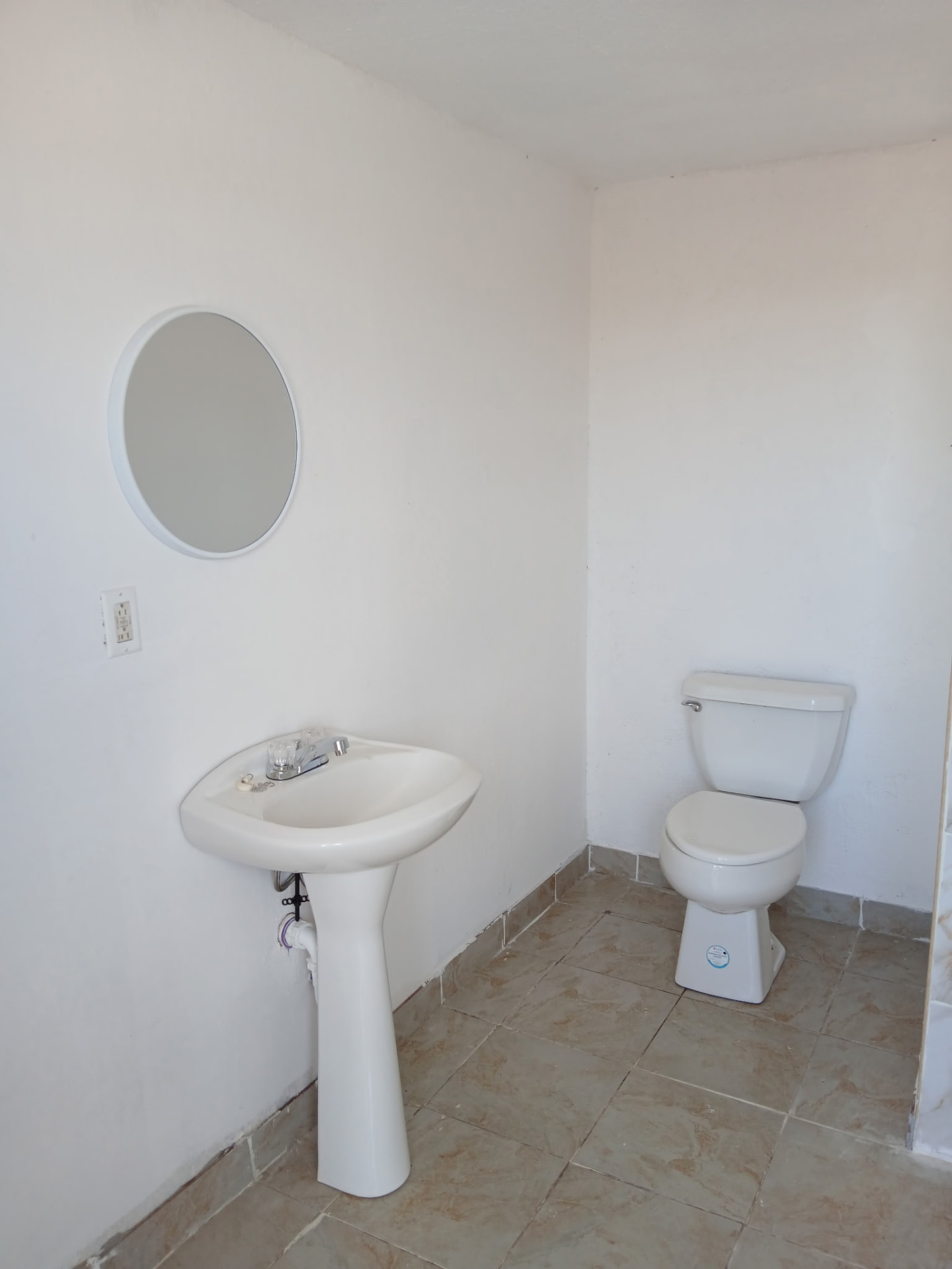 Clean guest restroom with pedestal sink, mirror, and toilet